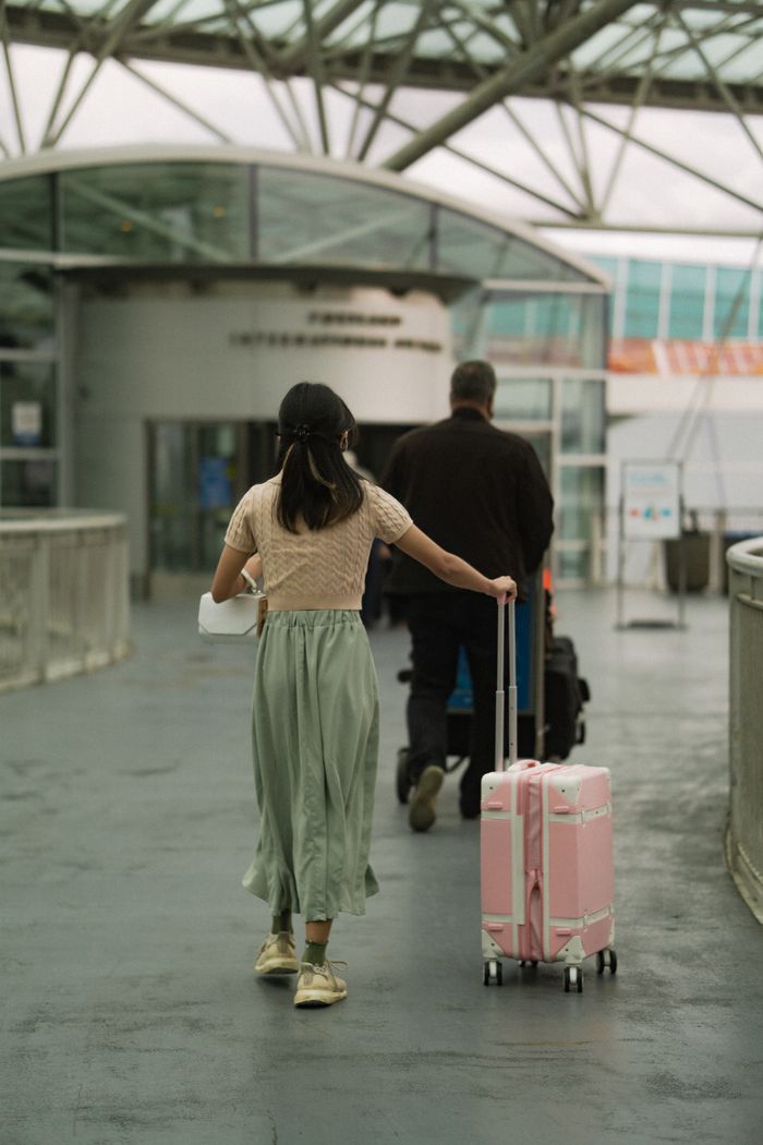 services-01 A man and woman with luggage entering an airport terminal, symbolizing travel and exploration.