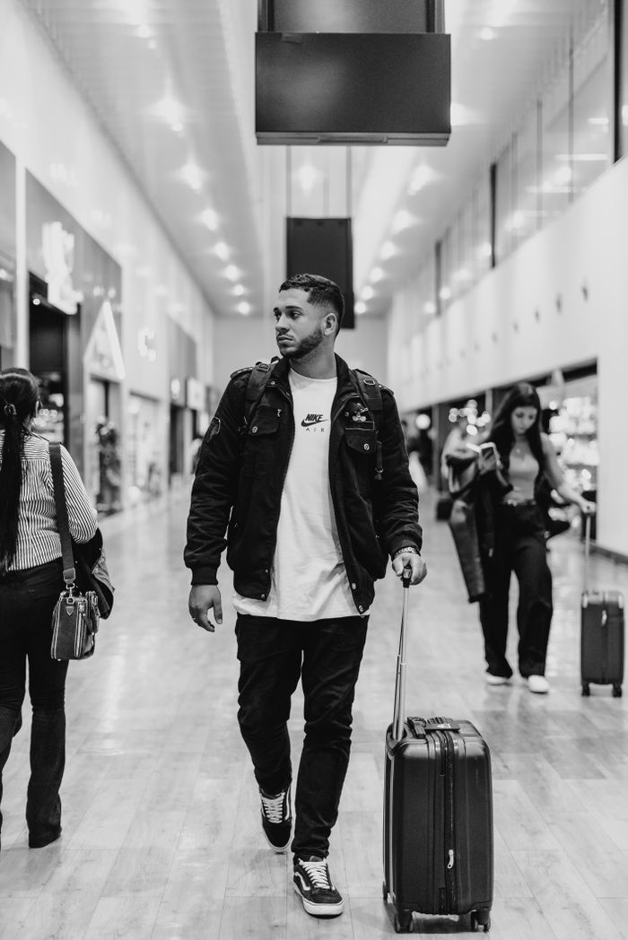 services-02 Man walking with luggage in a stylish airport terminal, capturing modern travel vibes.